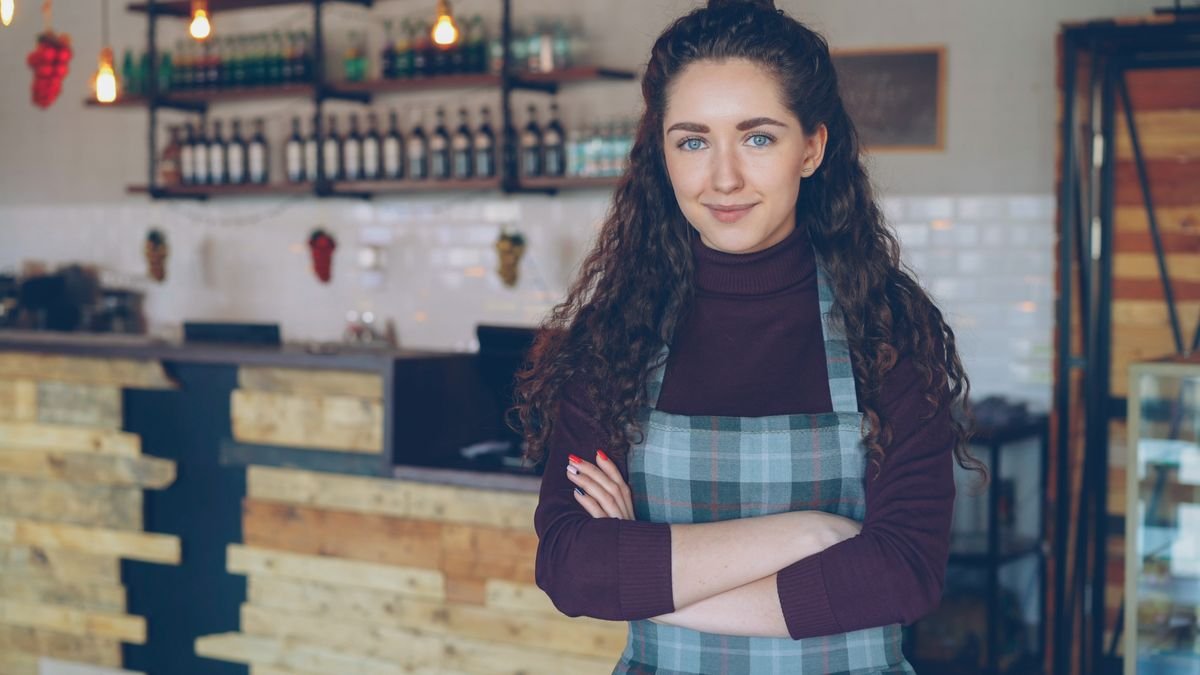 A café owner standing at the counter of a small timber-fitted shop