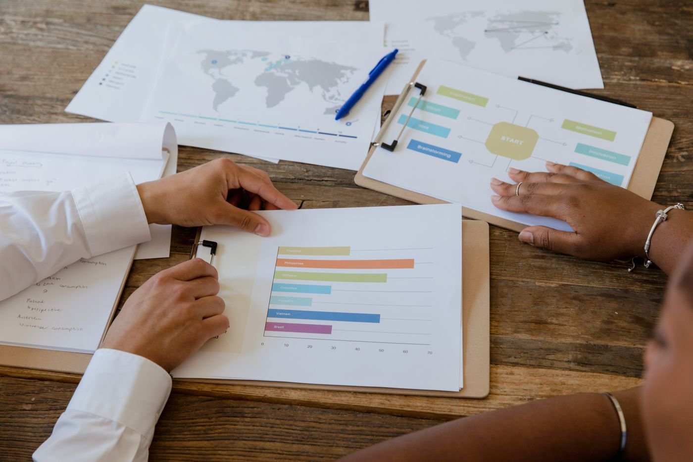 Two people comparing printed charts and a planning diagram across a timber table