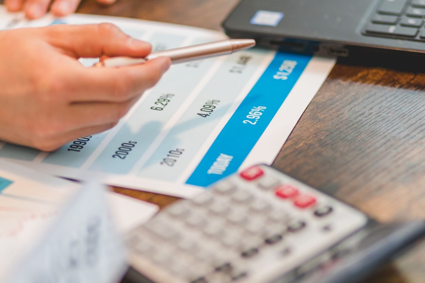 A pen resting on a printed rate schedule beside a laptop