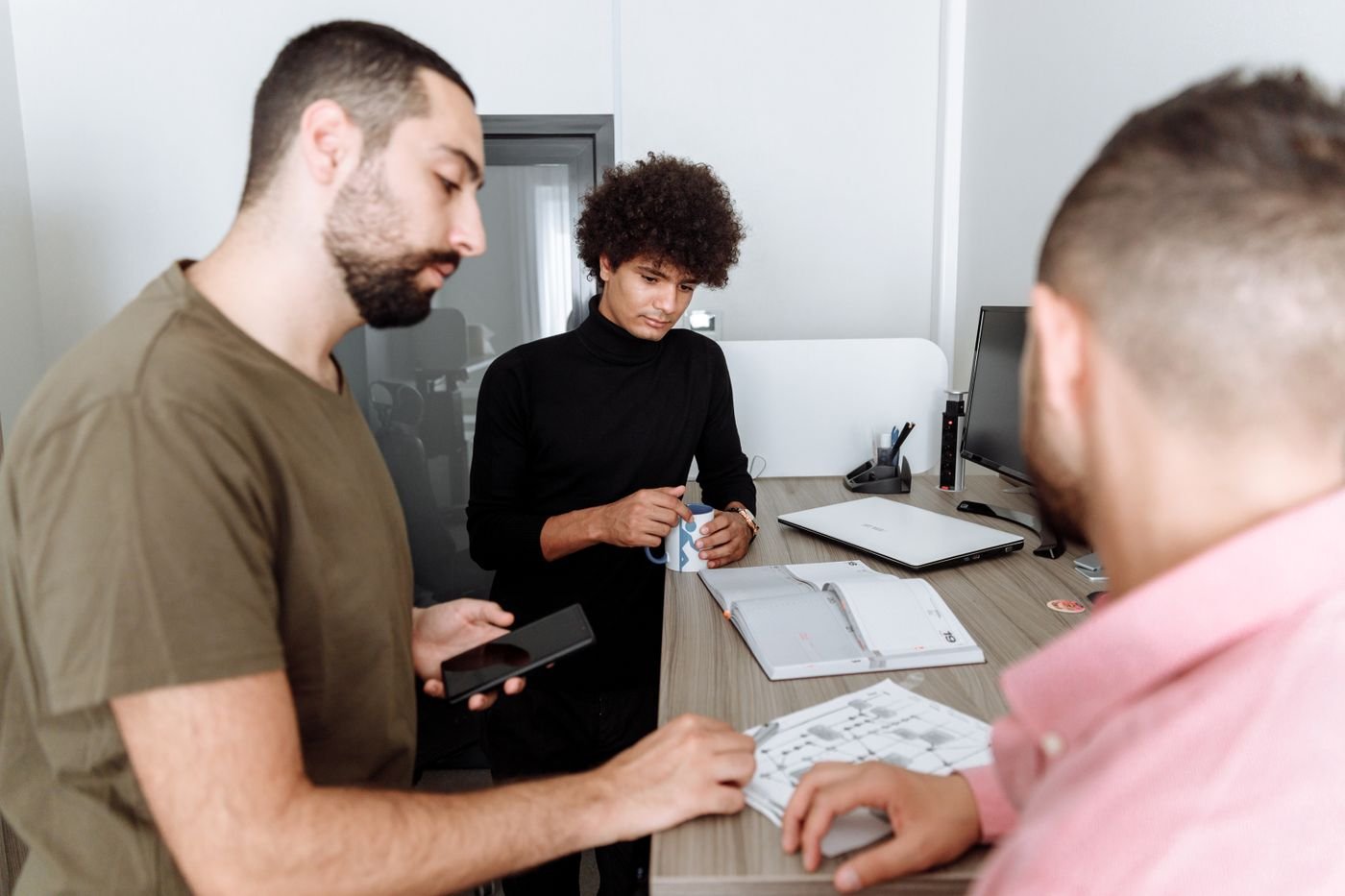 Three colleagues gathered around a desk in a small office