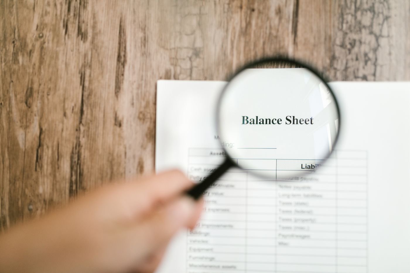 A magnifying glass held over a printed balance sheet